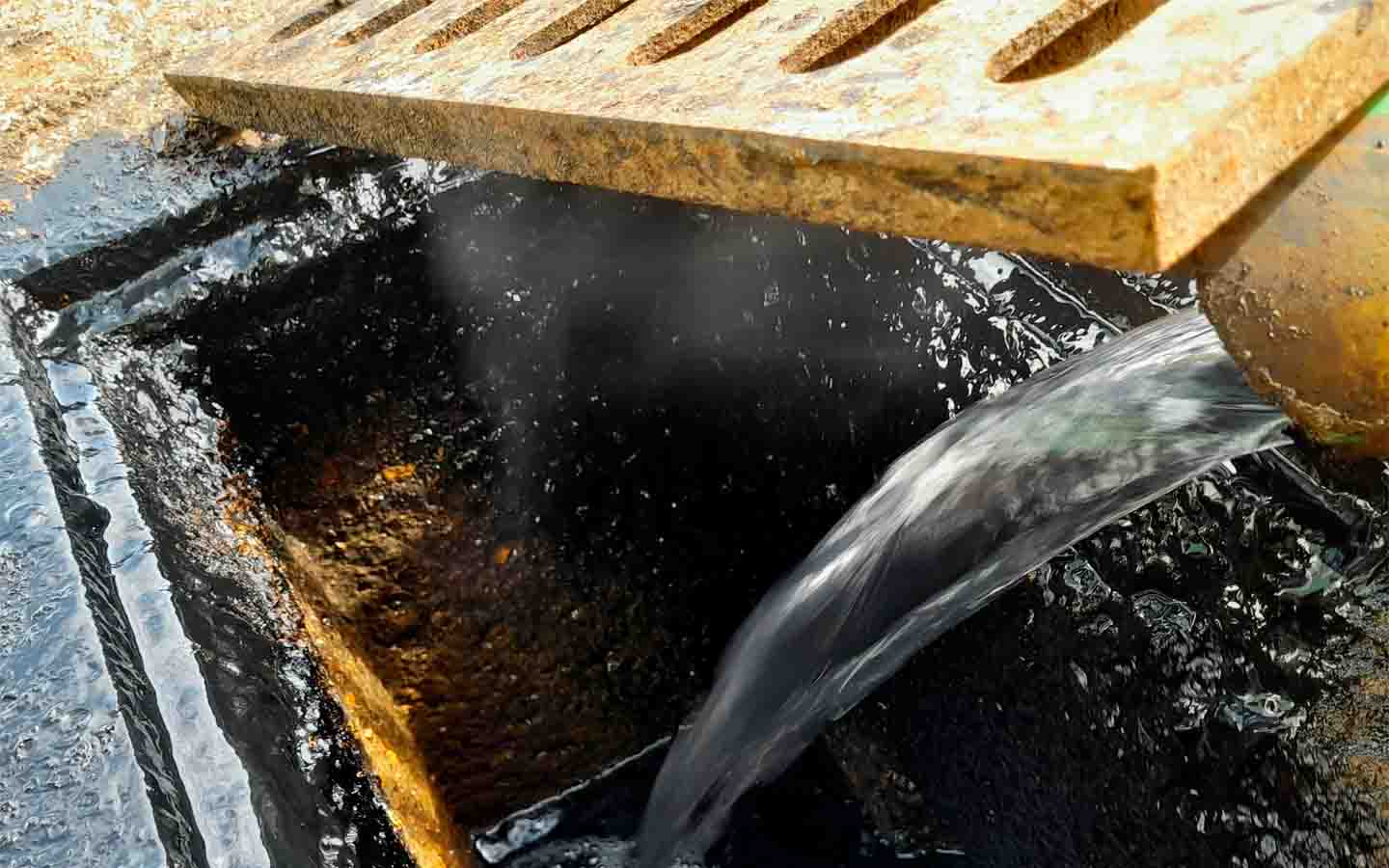 Agua fluyendo a desagüe bajo rejilla metálica