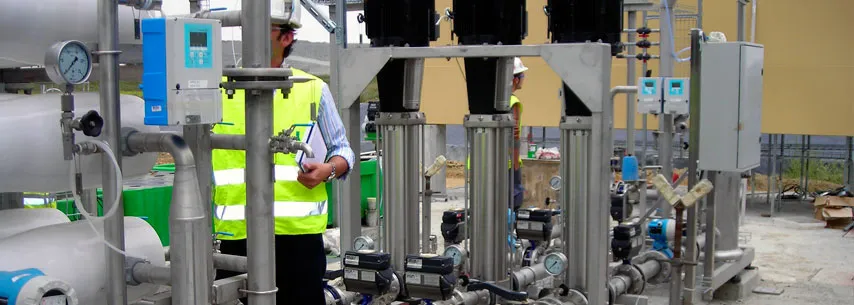 Trabajadores inspeccionando maquinaria industrial con tuberías y válvulas
