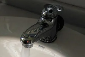 Grifo cromado abierto con agua corriendo