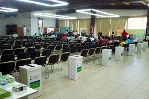 Sala con urnas y asistentes sentados